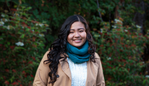 Image of a high school senior as she stands in front of lush foliage to illustrate senior photography.