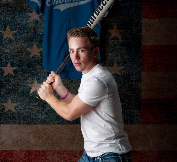 Image of a senior in a batting stance wearing a white t-shirt and jeans to illustrate senior photography.